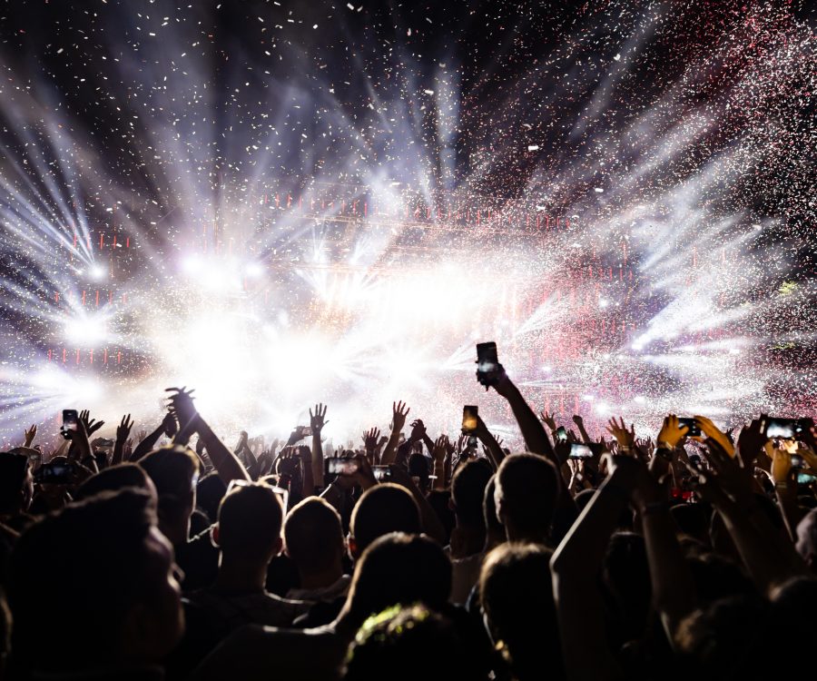 Excited audience watching confetti fireworks and having fun on music festival at night. Copy space.