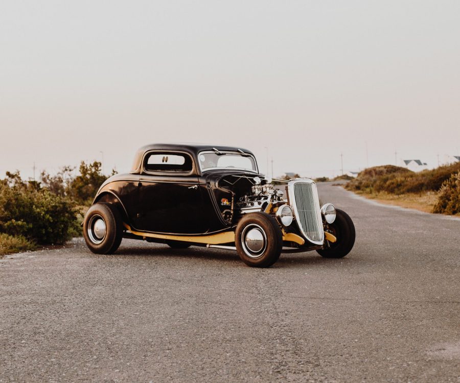 An old vintage car parked in the middle of the freeway road